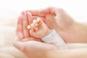newborn baby hand cradled in mother's hands
