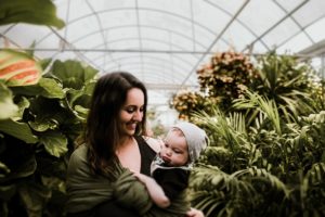Mom babywearing infant child inside greenhouse