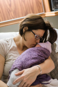 mother kissing newborn head